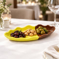 A ceramic leaf-shaped serving dish with a bright yellow glazed interior and a brown glazed exterior.
