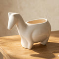 A white ceramic horse-shaped planter with a smooth glossy finish and a light beige interior