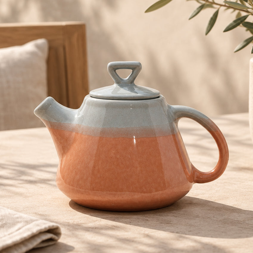 A pink and grey ceramic teapot with a kettle spout.